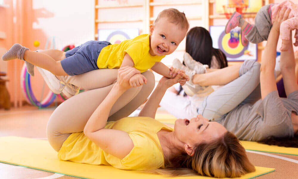 One year old boy laughing while being lifted on gym instructor's shins