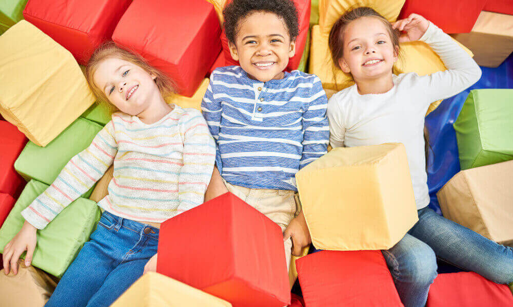 Three happy little kids playing in a foam pit.