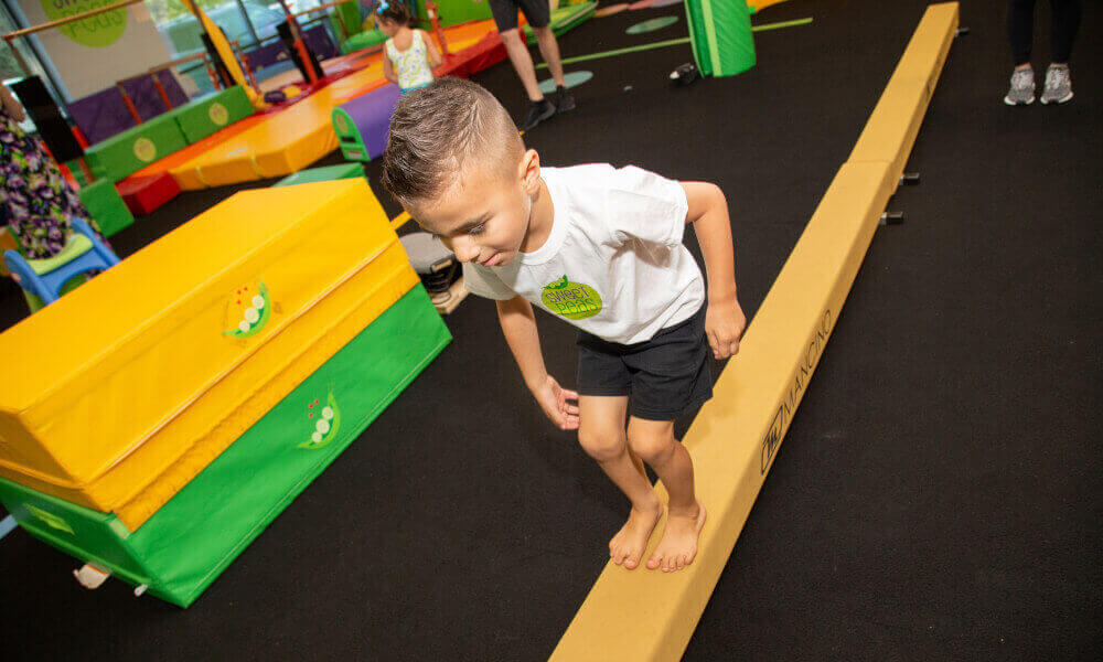 Happy boy on a wooden swing inside his room.